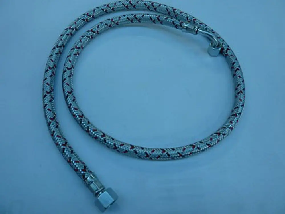 Flexibler Ölschlauch mit einer Ummantelung, hergestellt von Remeha, mit Metallanschlüssen an beiden Enden, auf heller Unterlage liegend.